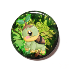 A cute chibi version of Turtwig from POkemon drawn by Camie M. Anderson on a handmade button